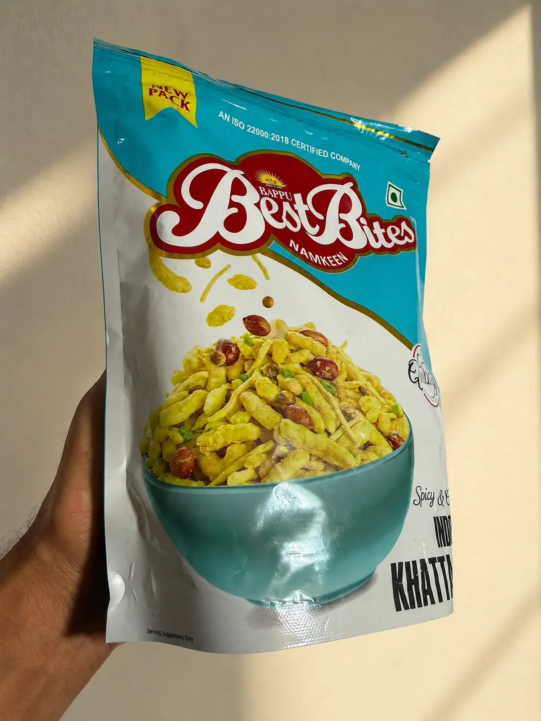 A hand holding an Indori Khatta Meetha pack